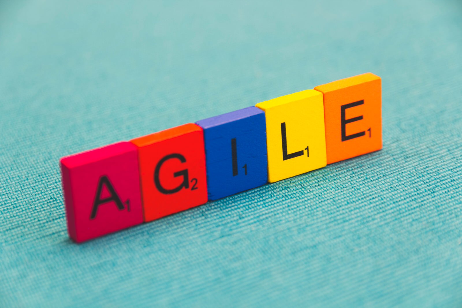 Unas fichas de madera muestran la palabra AGILE con cada letra de un color.