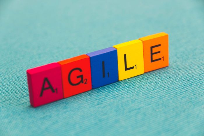 Unas fichas de madera muestran la palabra AGILE con cada letra de un color.
