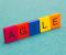 Unas fichas de madera muestran la palabra AGILE con cada letra de un color.
